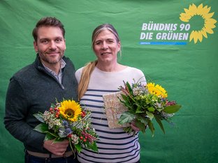 Portrait von Sylvia Berghoff und Julian Münster vor einem Banner der Bündnis 90 – Die Grünen